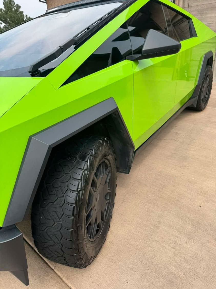 Side of a green Tesla Cybertruck with clean black wheels and tires