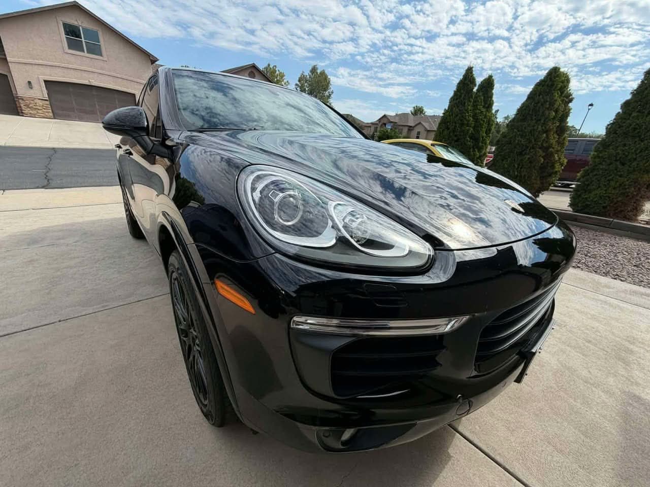 Black Porsche Cayenne with shiny, clean paint parked in a driveway