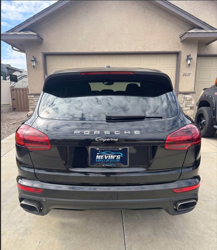Back of a freshly detailed black Porsche Cayenne with a Nevin's Mobile Detailing plate frame